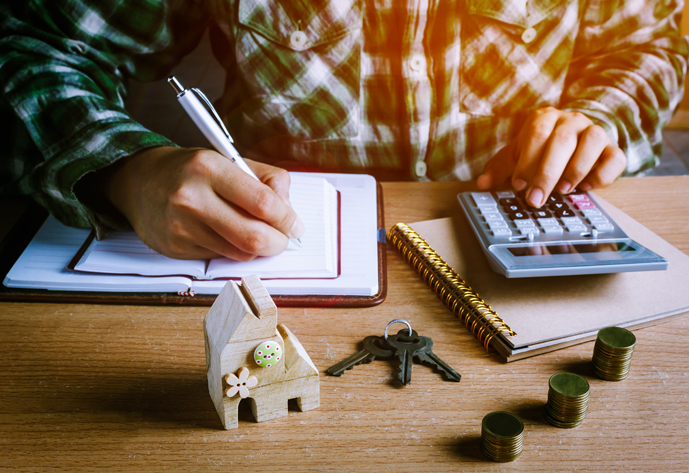 Selective focus wood home key and step up gold coin or currency on wooden table with document.Blur hand man calculate finance and writing on notebook at home office desk.business concept background.